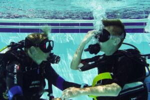 Child learning scuba diving in swimming pool in Devon